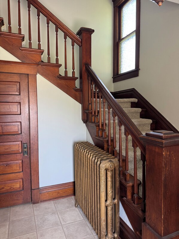 A wooden staircase with a radiator at the bottom.