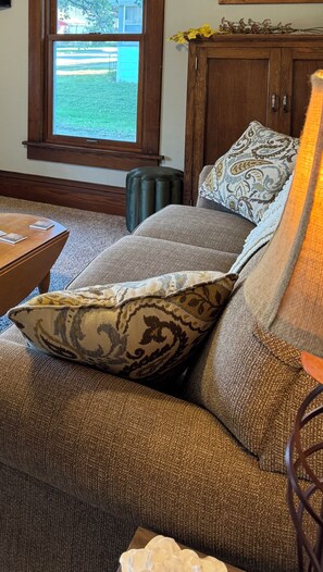 A living room with a sofa, a coffee table, and a window with a view of a yard.
