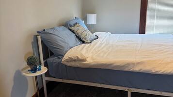 A bedroom with a single bed, a bedside table with a lamp, and a small potted plant.