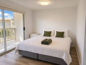 A bedroom with a bed, pillows, a nightstand, and a sliding glass door leading to an outdoor area.