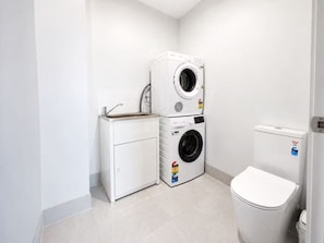 A compact laundry room with a washing machine, dryer, and a small cabinet.