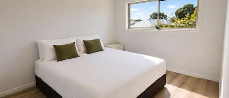 Une chambre à coucher avec un grand lit, une table de chevet, une fenêtre donnant sur un beau paysage et un luminaire au plafond.
