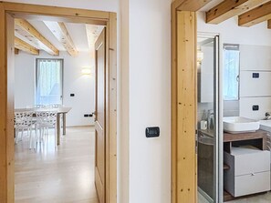 Ein Zimmer mit Holzboden, einer weißen Wand und einem Badezimmer mit Spiegel und Waschbecken.