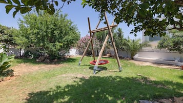 Un patio trasero con un columpio, un trampolín y diferentes plantas.