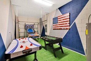 Une pièce équipée d’un baby-foot, d’une table de ping-pong et d’un panier de basket.