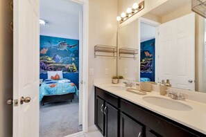 Une salle de bain avec un grand miroir, un lavabo et un espace douche.