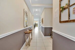 A hallway with a wooden bench, framed artwork, and a tiled floor. - Exclusive 6 bedroom family vacation home! (Kissimmee)