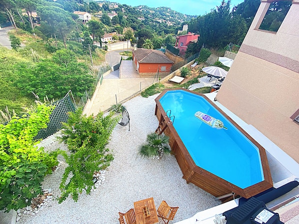 Eine erhöhte Perspektive eines Wohngebiets mit Schwimmbecken, einer Holzterrasse und Blick auf die umliegende Nachbarschaft.