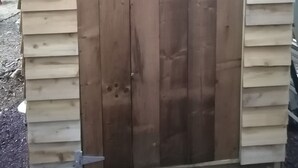 A wooden door with a crescent moon cutout, a metal latch, and a sliding door mechanism.