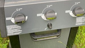 A grill with three burgers cooking on it.