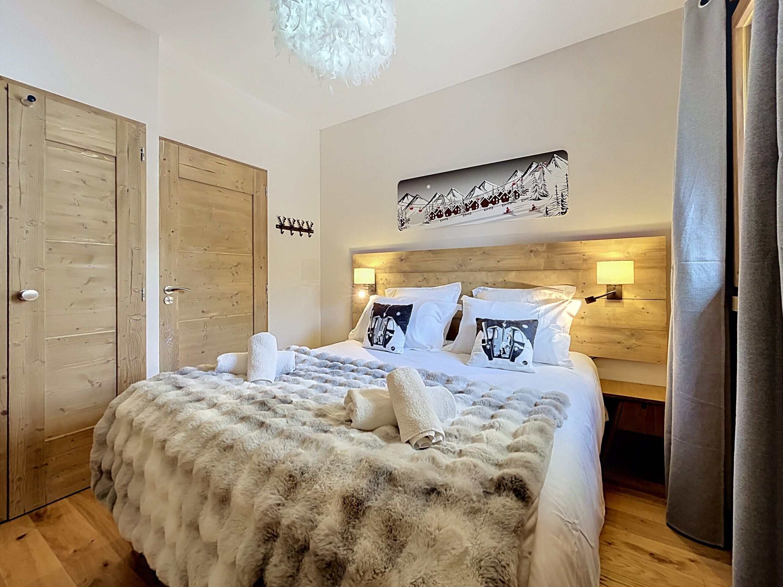 Habitación de hotel con una cama grande, cabecera de madera, dos lámparas de noche, una manta suave y una obra de arte colgada en la pared.