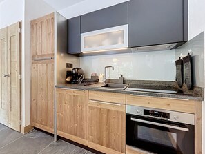 A modern kitchen with wooden cabinets, a stainless steel sink, and a Bosch oven. - Santal - Les Gets - Selena Residence (Les Gets)