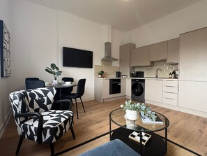A compact living space with a dining area, kitchen, and a flat-screen TV mounted on the wall. - 2-Bath, 2 Bedroom, Free Parking – Birkdale (Southport)