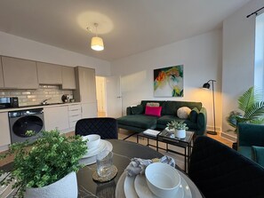 A modern living space with a kitchen, dining area, and a green sofa. - 2-Bath, 2 Bedroom, Free Parking – Birkdale (Southport)