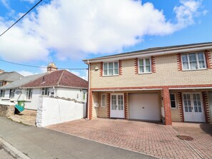 A two-story residential building with a garage, a brick facade, and a clear sky. - 1 Tideways (Bideford)