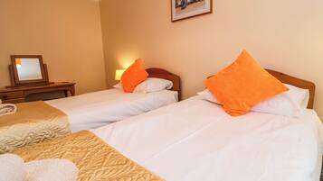 A hotel room with two beds, a bedside table, a lamp, and a framed picture on the wall.