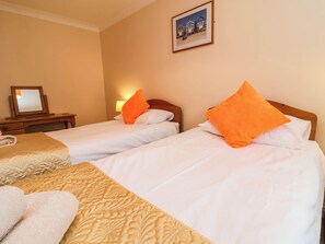 A hotel room with two beds, a bedside table, a lamp, and a framed picture on the wall. - 1 Tideways (Bideford)