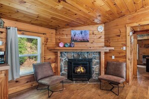 A cozy cabin interior with a stone fireplace, wooden walls, and two leather chairs. - 10 Min to Downtown | Firepit + Pet Friendly (Blue Ridge)