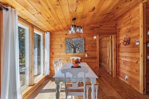 A wooden interior with a dining table, chairs, a chandelier, and a painting on the wall. - 10 Min to Downtown | Firepit + Pet Friendly (Blue Ridge)
