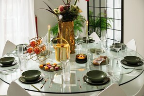 Une table ronde en verre, mise pour le dîner, avec des assiettes, des couverts, des verres et un chandelier en guise de centre de table.