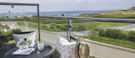A table with a glass top, a patterned cushion, and a straw hat.