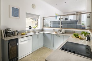 A modern kitchen with a built-in oven, a coffee maker, and a window with a view of the outdoors. - Croft House - sleeps 10 guests  in 4 bedrooms (Widemouth Bay)