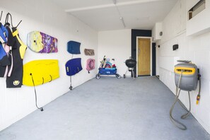 A garage with surfboards, a barbecue grill, and a power tool. - Croft House - sleeps 10 guests  in 4 bedrooms (Widemouth Bay)
