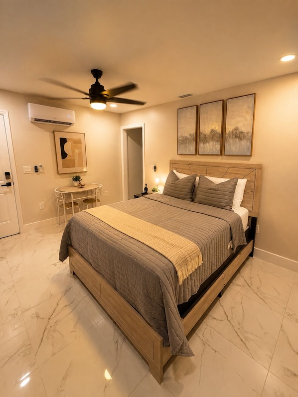 A bedroom with a bed, a desk, and a ceiling fan. - Flora Luxe States (Tampa)