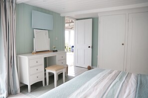 Een slaapkamer met een bed, een kaptafel met spiegel, een stoel en een kledingkast.