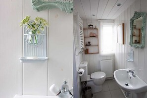 Een badkamer met toilet, wastafel en een plankje met een bloemenvaas.