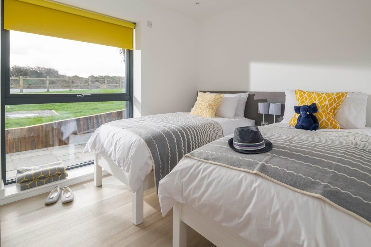 A hotel room with two beds, a large window, and a view of the outdoors.