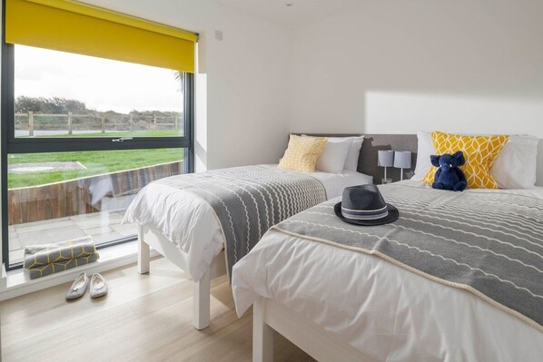 A hotel room with two beds, a large window, and a view of the outdoors. - Dune Lodge - sleeps 4 guests  in 2 bedrooms (Hayle)