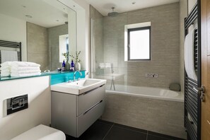 Een moderne badkamer met een douchecabine van glas, een wit wastafelmeubel en een bad.