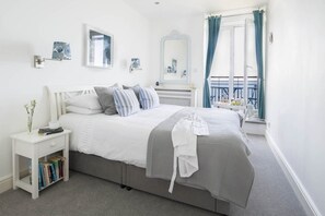 Een slaapkamer met een bed, nachtkastje en een raam met gordijnen.