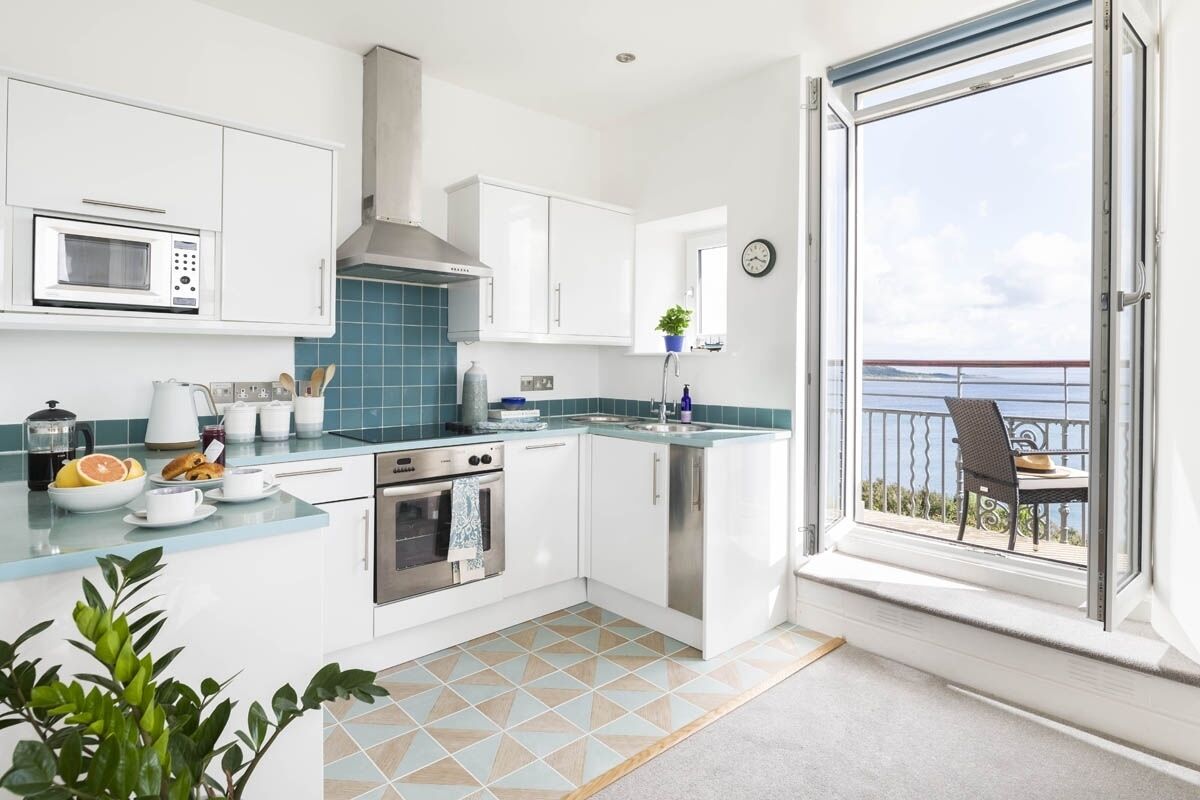 A modern kitchen with white cabinets, a stainless steel oven, and a blue tiled backsplash.