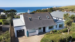 A coastal house with a sloped roof, a garage, and a view of the sea. - Fourburrows - sleeps 10 guests in 5 bedrooms (Mawgan Porth)