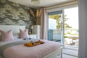 A bedroom with a bed, bedside table, and a view of the outdoors. - Fourburrows - sleeps 10 guests in 5 bedrooms (Mawgan Porth)