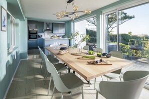 A modern kitchen with a dining area, large windows, and a view of the outdoors. - Fourburrows - sleeps 10 guests in 5 bedrooms (Mawgan Porth)