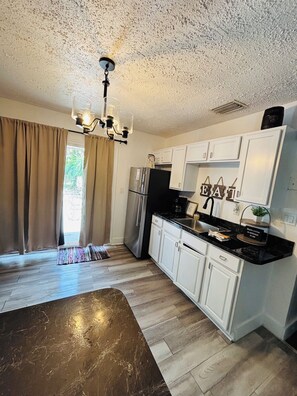 A kitchen with white cabinets, a stainless steel refrigerator, and a chandelier. - Beautiful 1-bedroom guest house with AC in Port St. Lucie with Pool (Port St. Lucie)