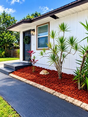 A modern house with a dark door, a window with blinds, and a small porch with steps. - Beautiful 1-bedroom guest house with AC in Port St. Lucie with Pool (Port St. Lucie)