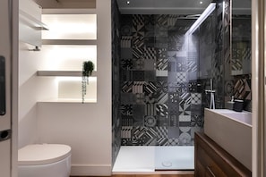 A modern bathroom with a toilet, a shower area, and a vanity with a mirror. - Old Town Prestige Loft by Flatinrome (ROMA)