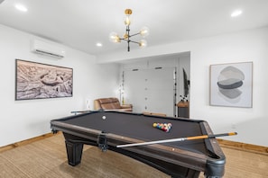 Une table de billard avec les billes, un fauteuil en cuir et une queue de billard.