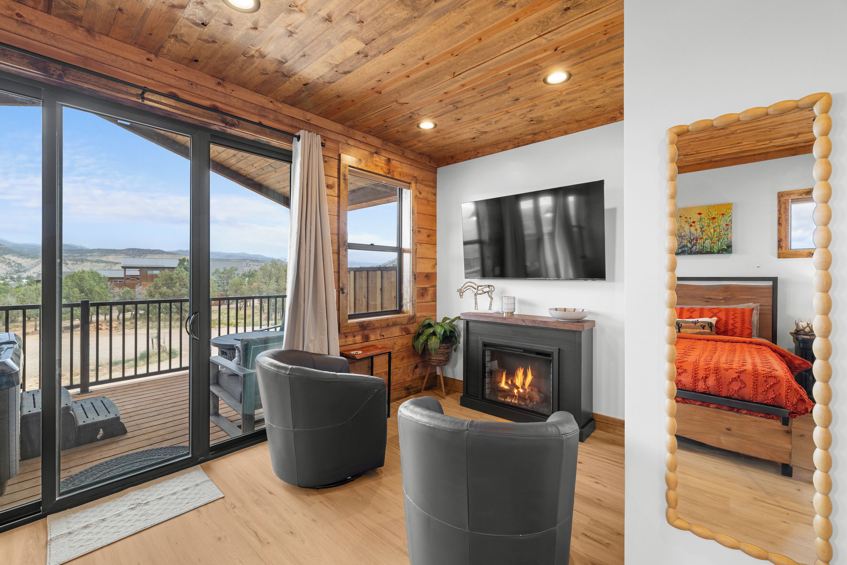 Ein geräumiger Wohnbereich mit Kamin, Fernseher und einem Balkon mit Bergblick.