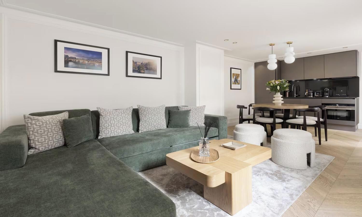 A modern living room with a sectional sofa, a coffee table, and a dining area with a kitchen in the background.