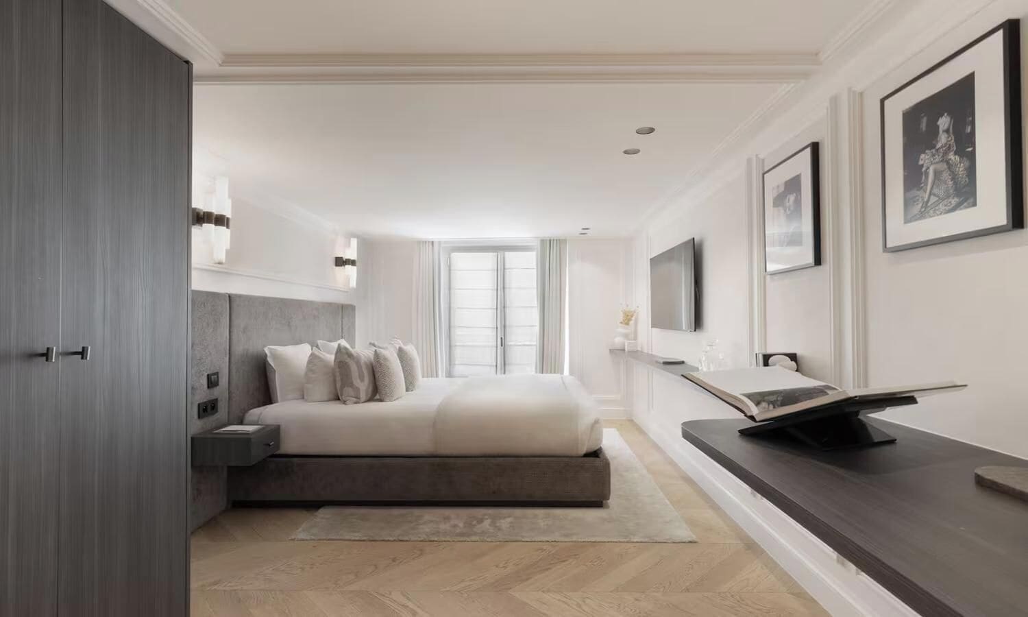 A modern bedroom with a bed, bedside table, and a flat-screen TV.