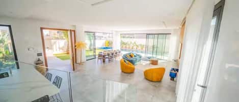 A spacious living area with a dining table and chairs, a pool, and a bright, open design.