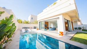Une maison moderne dotée d’une piscine, d’un espace extérieur aménagé et d’un jardin bien entretenu.