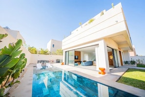 Uma casa moderna com piscina, área de estar externa e um jardim bem cuidado.