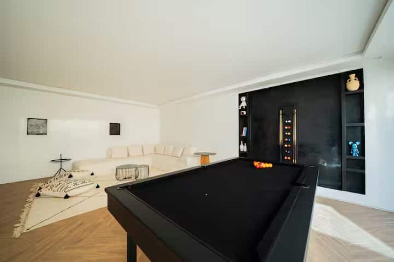 A modern living room with a pool table, a sofa, and a decorative rug.