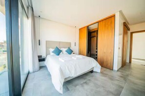 Ein modernes Schlafzimmer mit einem großen Bett, einem begehbaren Kleiderschrank und Blick durch ein großes Fenster.